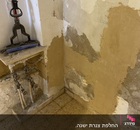 צינורות מים ישנים על קיר מתקלף